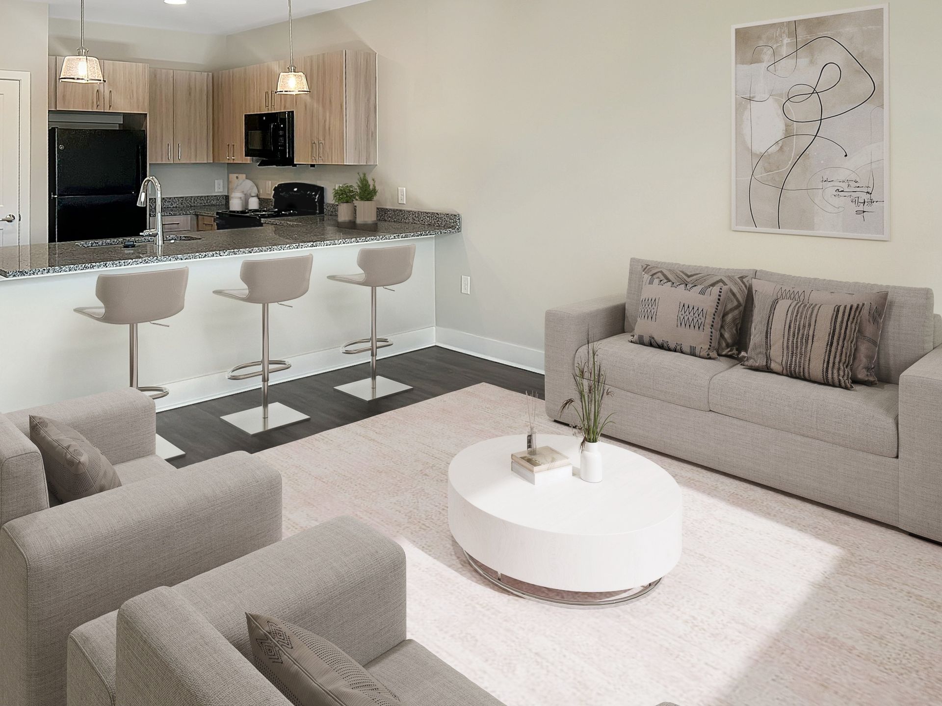 Open-concept living area with a kitchen island, three bar stools, and gray couches.