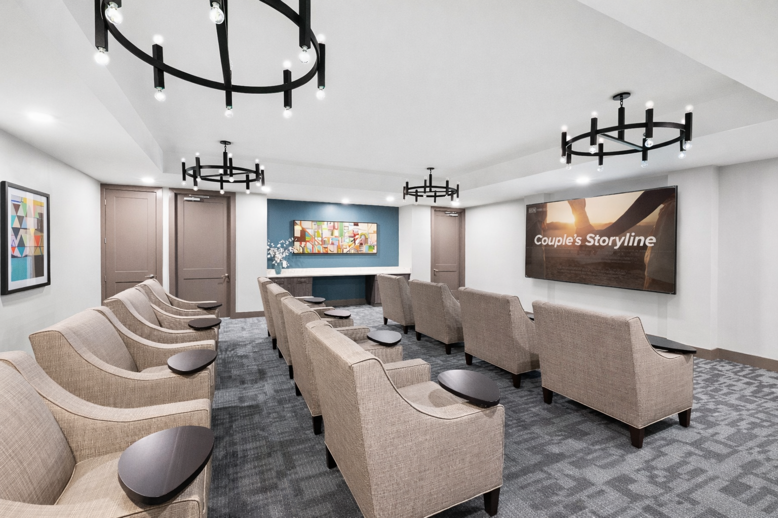 Modern waiting room with beige chairs, gray carpet, black ceiling lights, and wall art including “Creative Storytelling.”