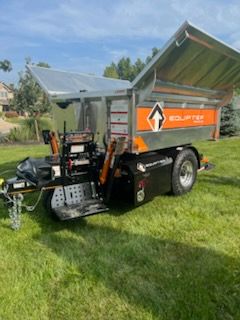 A dump truck is parked in a lush green field.