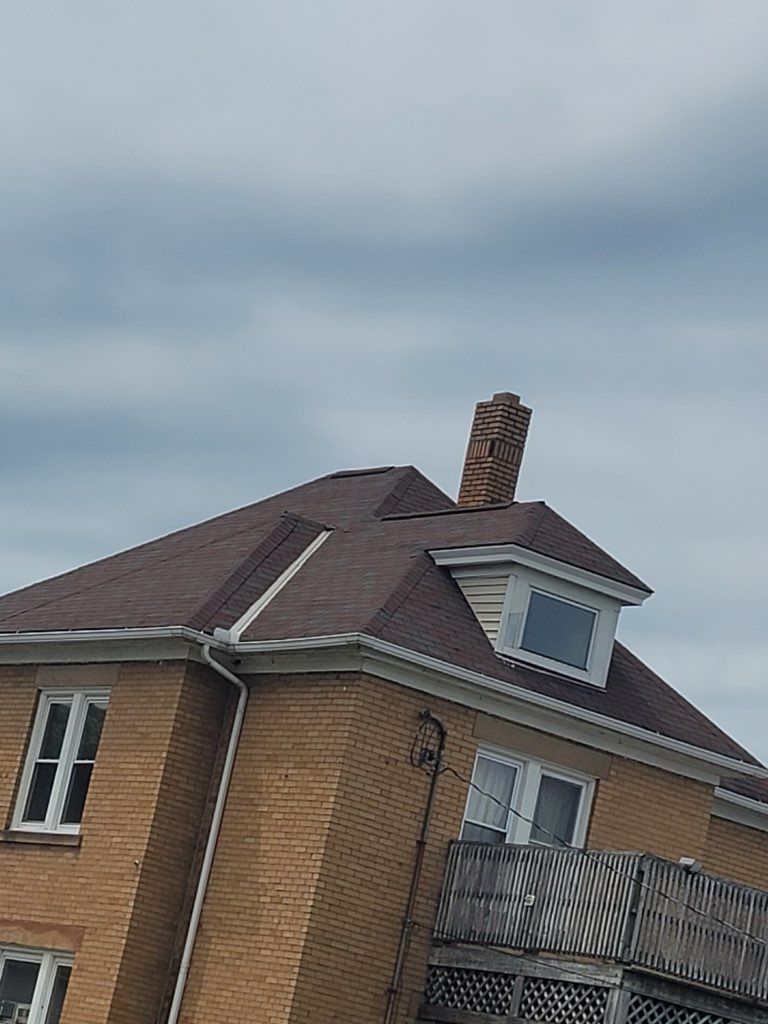A large brick house with a chimney on the roof.