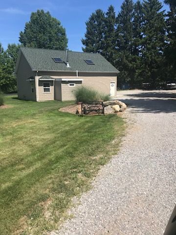 A house with a green roof is sitting on top of a lush green field.