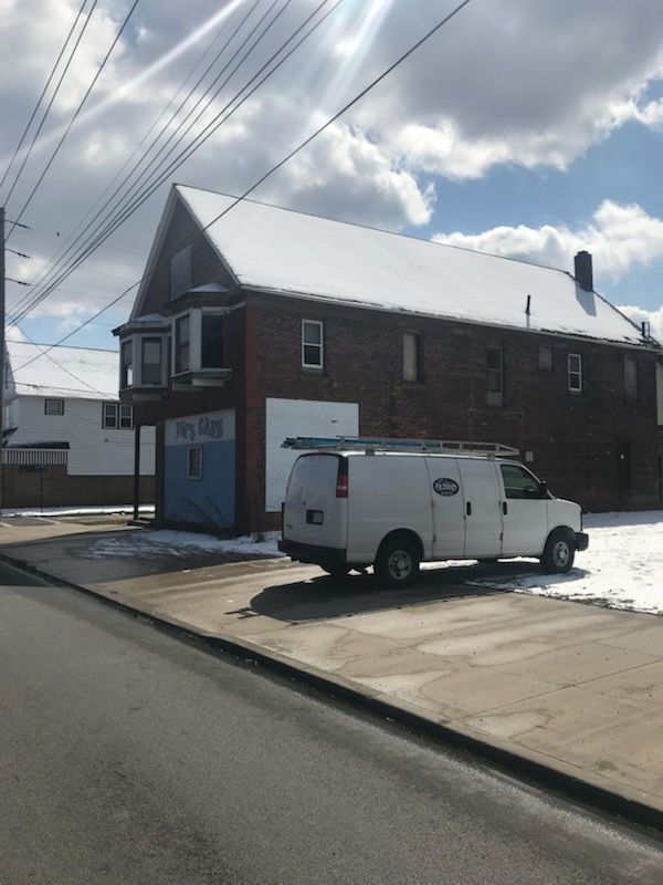 A white van is parked in front of a brick building