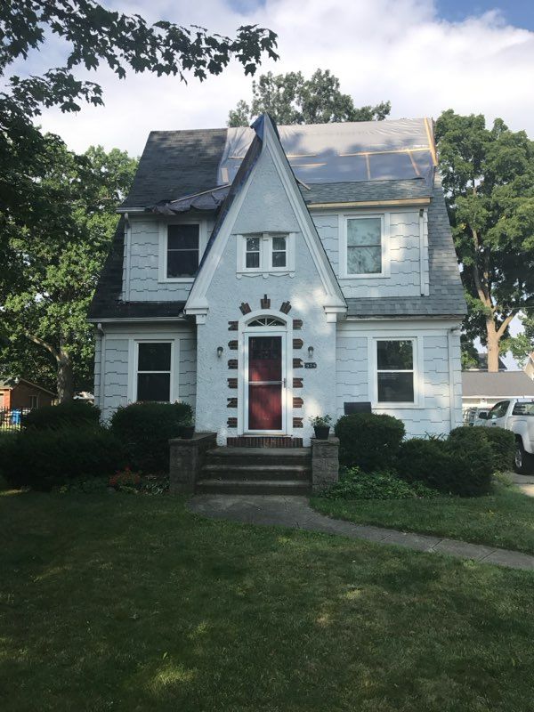 A white house with a red door and a black roof