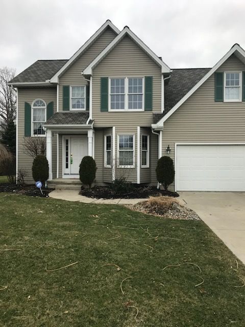 A large house with green shutters and a white garage door.