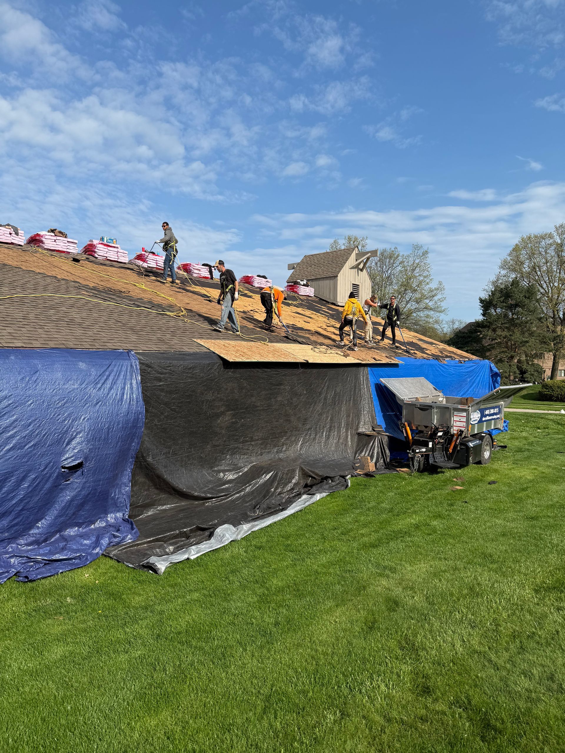 A group of people are working on the roof of a house.