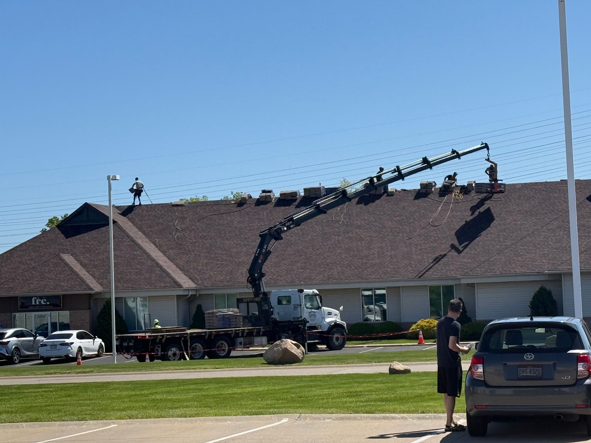 A man is standing in front of a building with a crane on the roof.