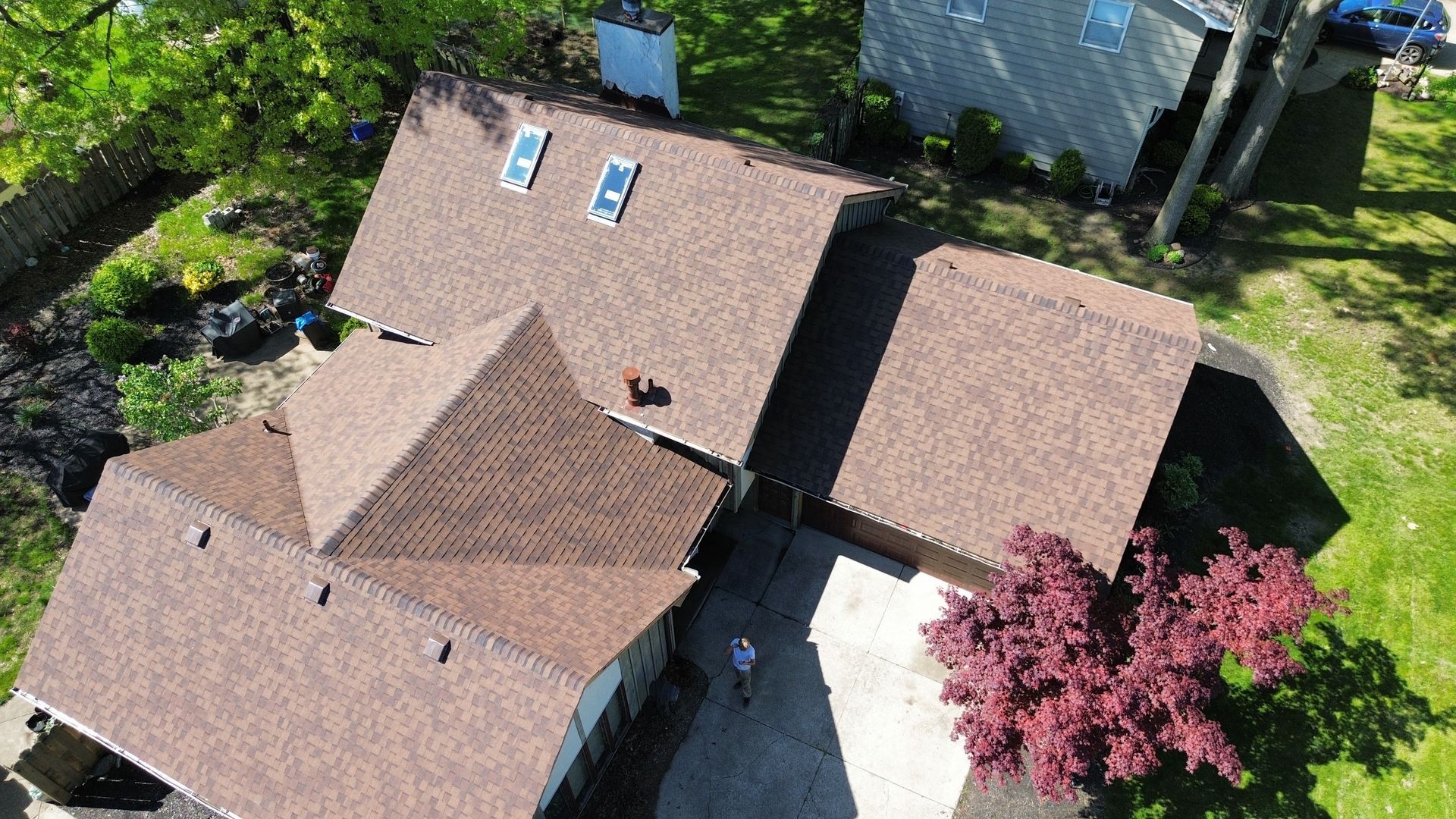 An aerial view of a house with a brown roof surrounded by trees.