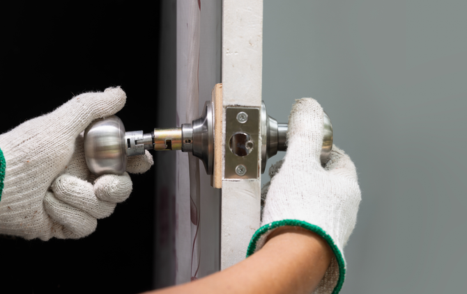 A person is installing a door knob on a door.