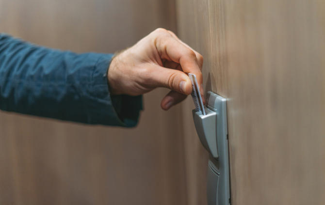 A person is inserting a credit card into a door lock.