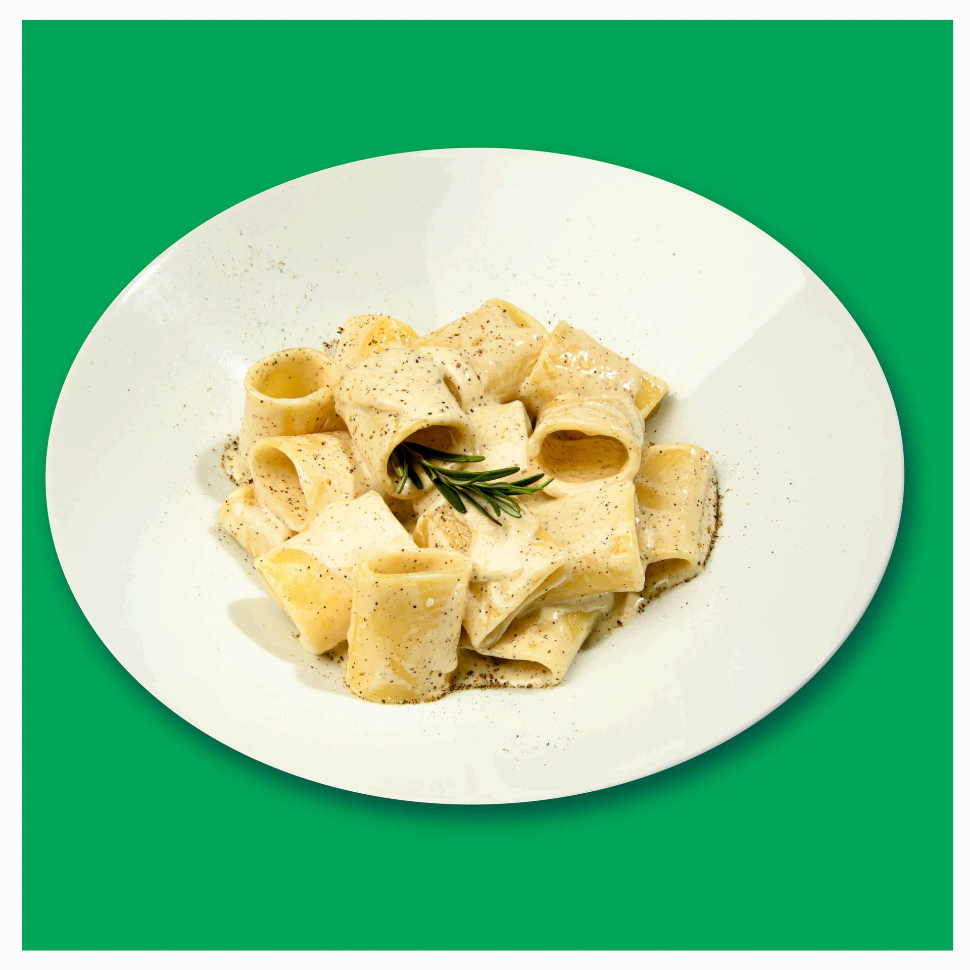 Un piatto bianco con sopra pasta e salsa su uno sfondo verde.