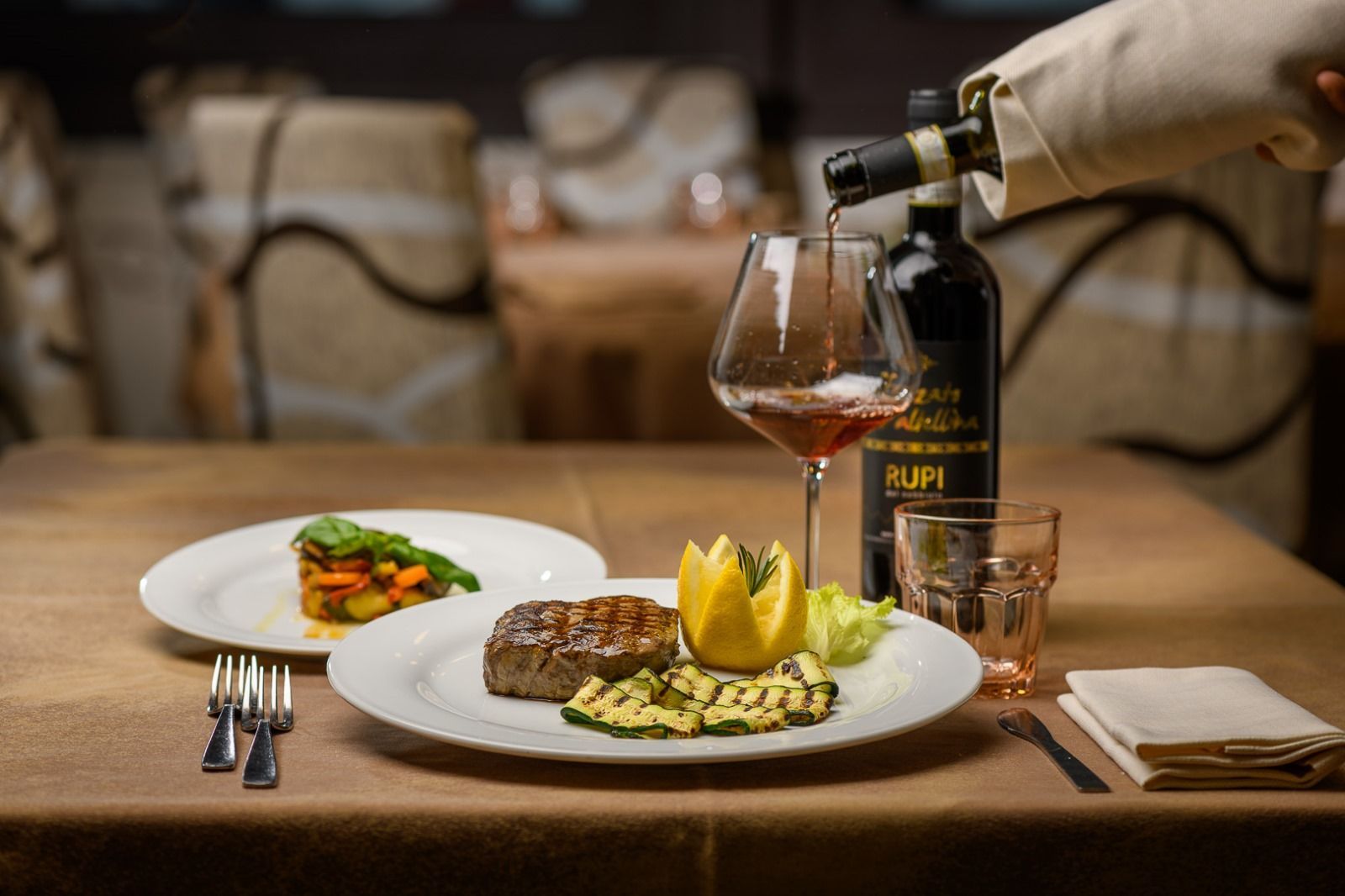 Un piatto di pasta con broccoli e patate su un tavolo con un bicchiere di vino.