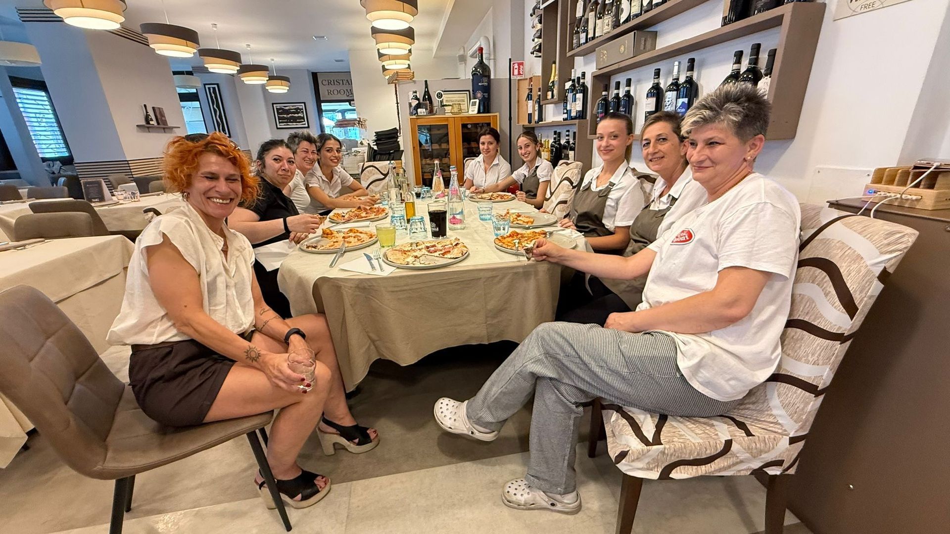 Un piatto di cibo con pomodori e mozzarella su un tavolo con un bicchiere di vino.