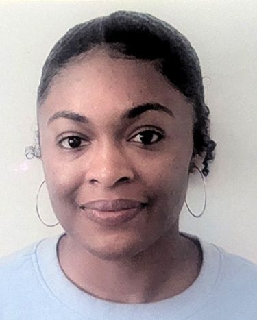 A woman wearing hoop earrings and a blue shirt is smiling for the camera.