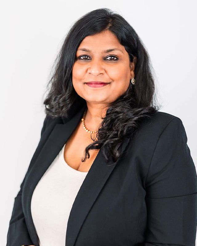 A woman in a black jacket and white shirt is smiling for the camera.