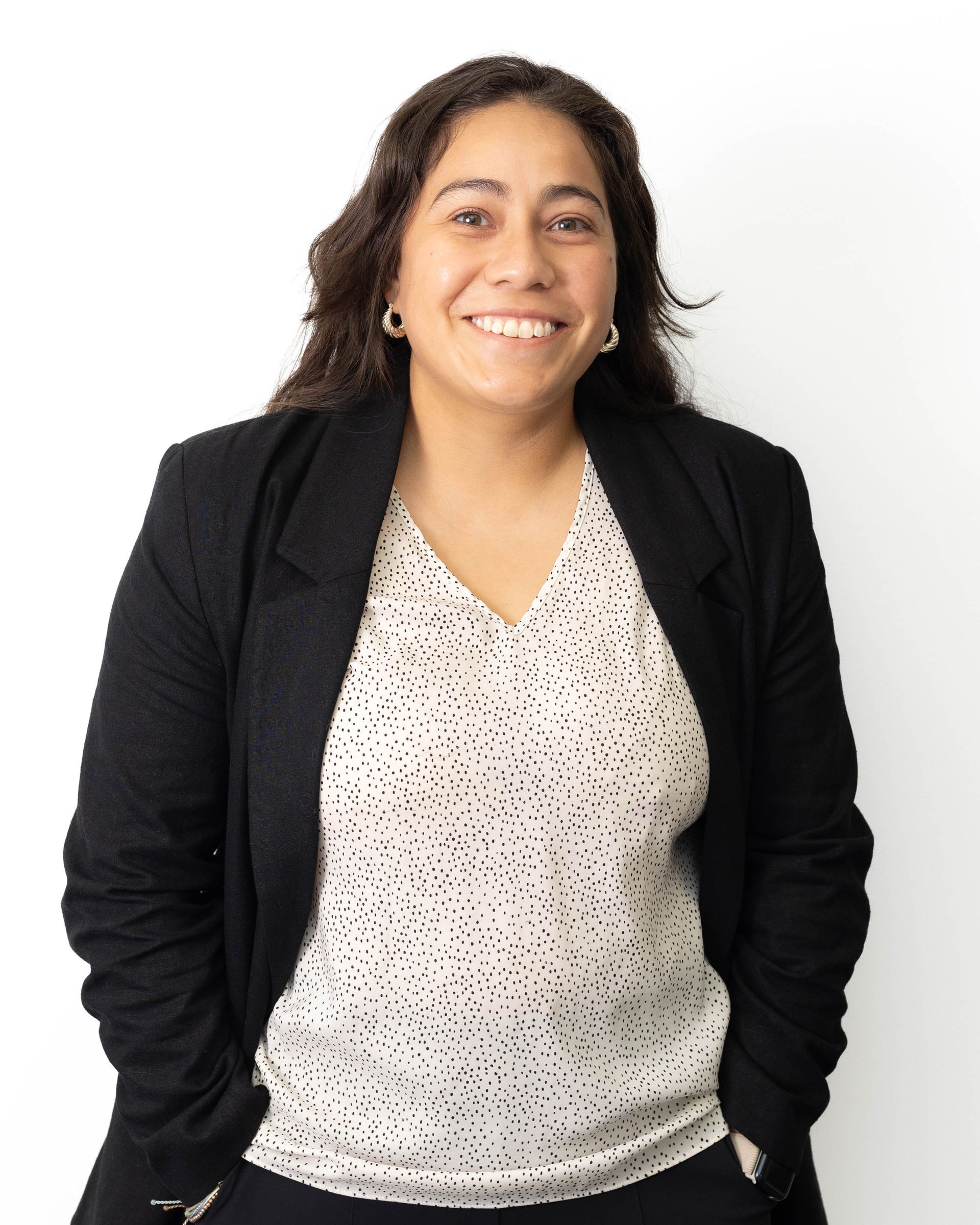 A woman wearing a black jacket and a white shirt is smiling.