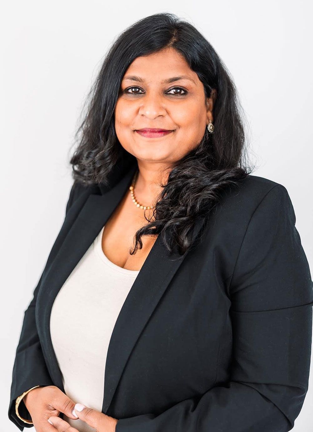 A woman in a black jacket and white shirt is smiling for the camera.