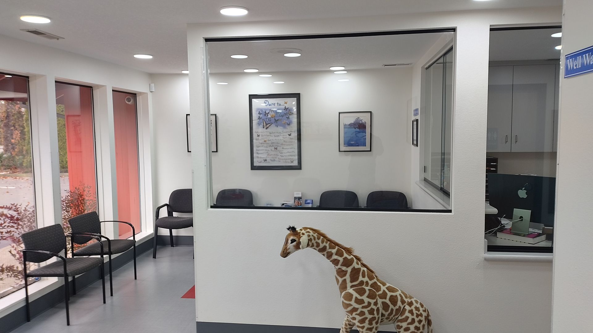 A stuffed giraffe is sitting in a waiting room.