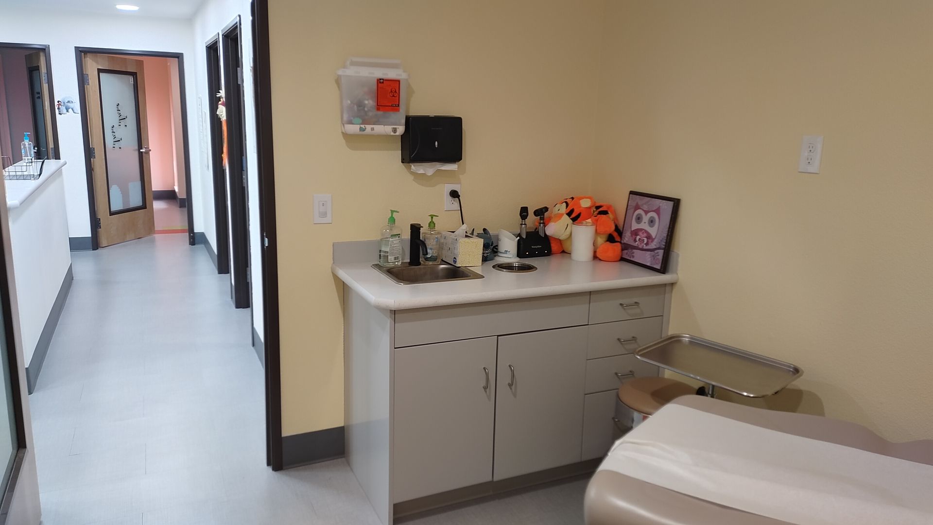 A doctor 's office with a table and a sink.