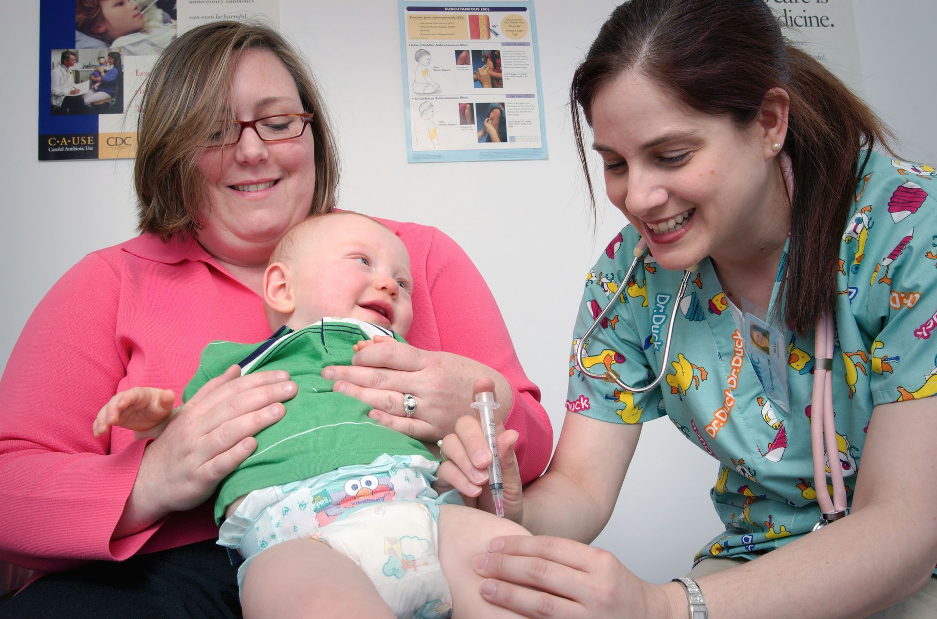 A woman is holding a baby while a nurse gives it an injection