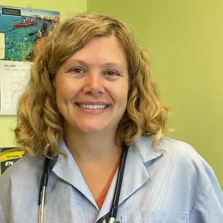 A woman with a stethoscope around her neck smiles for the camera