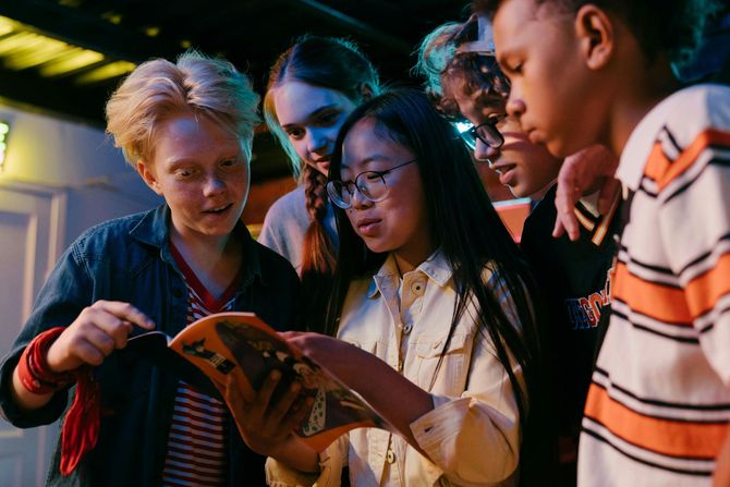 A group of young people are looking at a book together.