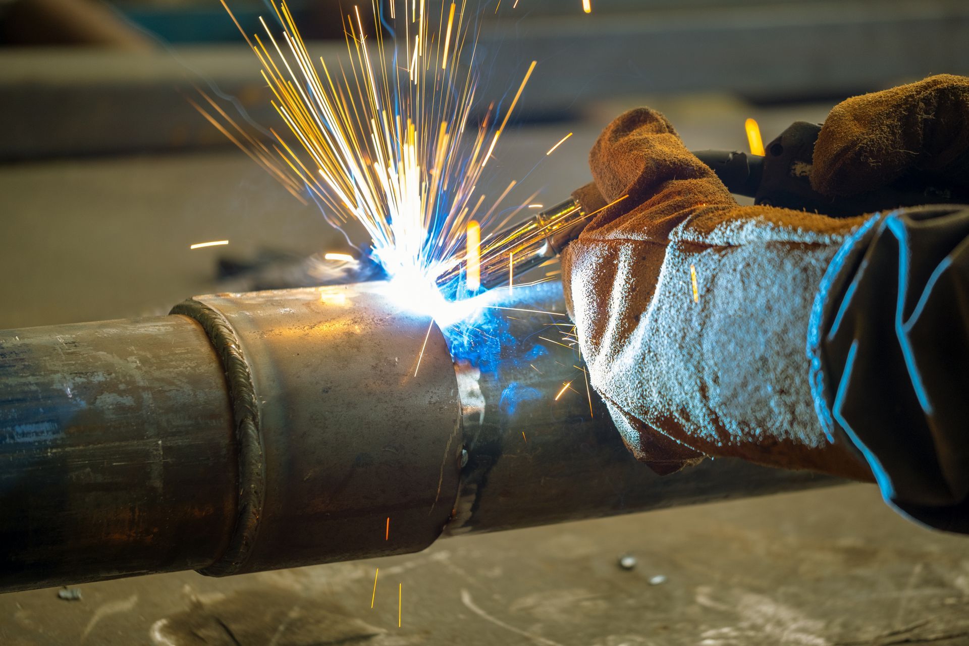 A person is welding a metal pipe with sparks coming out of it.