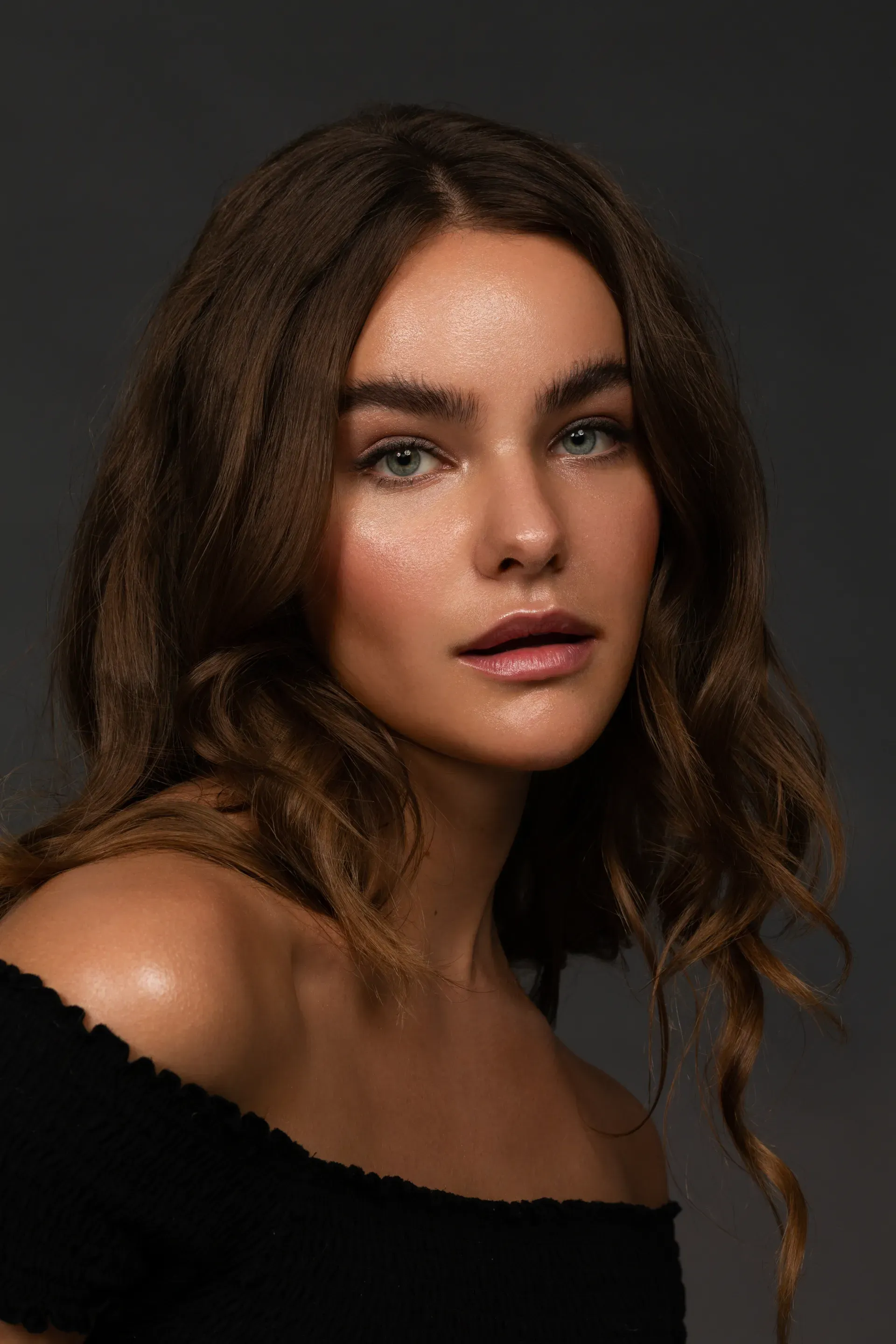 portrait dunkelhaariges model mit natuerlichen augenbrauen und glΓ€nzender haut dezent geschminkt