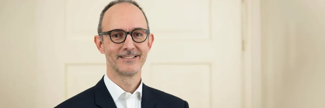 Finanzberater im Anzug und mit Brille, mattierte Haut und perfekt gestylt durch Visagistin