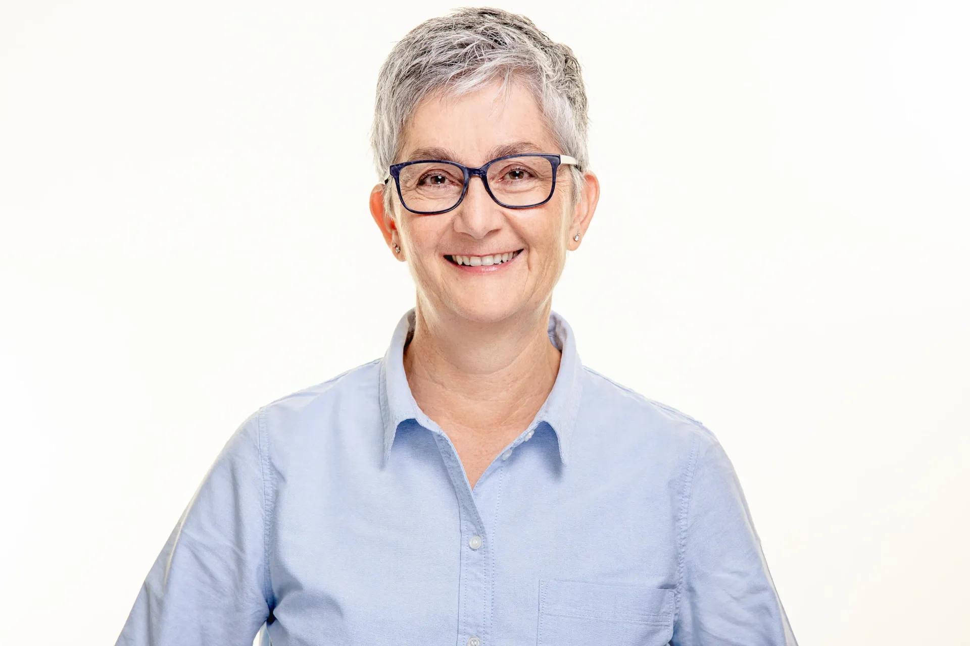 Aeltere reife Dame mit grauen Haaren und Brille laechelt frisch gestylt fΓΌr Corporate Fotoshooting