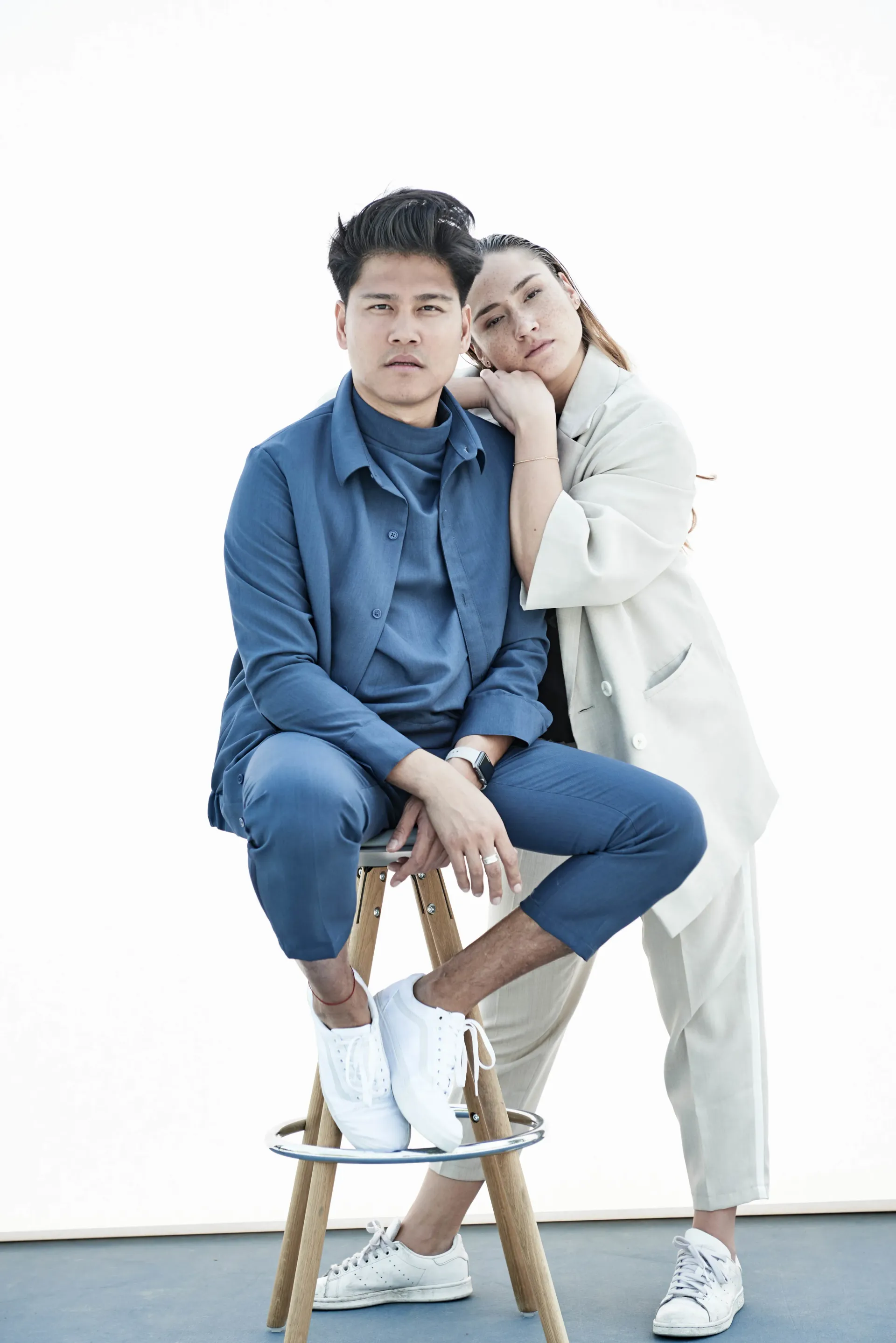 Our. Fashion Inhaber und Designer posiert mit Model auf Barhocker, locker frisiert in Unisexmode