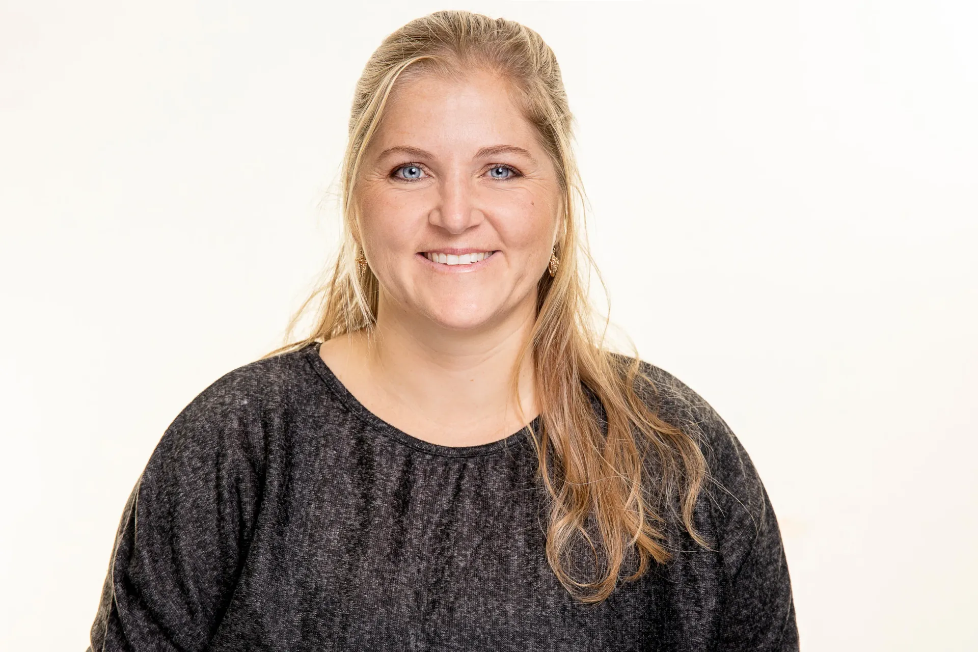 Sympathische BΓΌroangestellte laechelt fΓΌr Mitarbeiterportraits, dezent geschminkt, strahlende blaue Augen