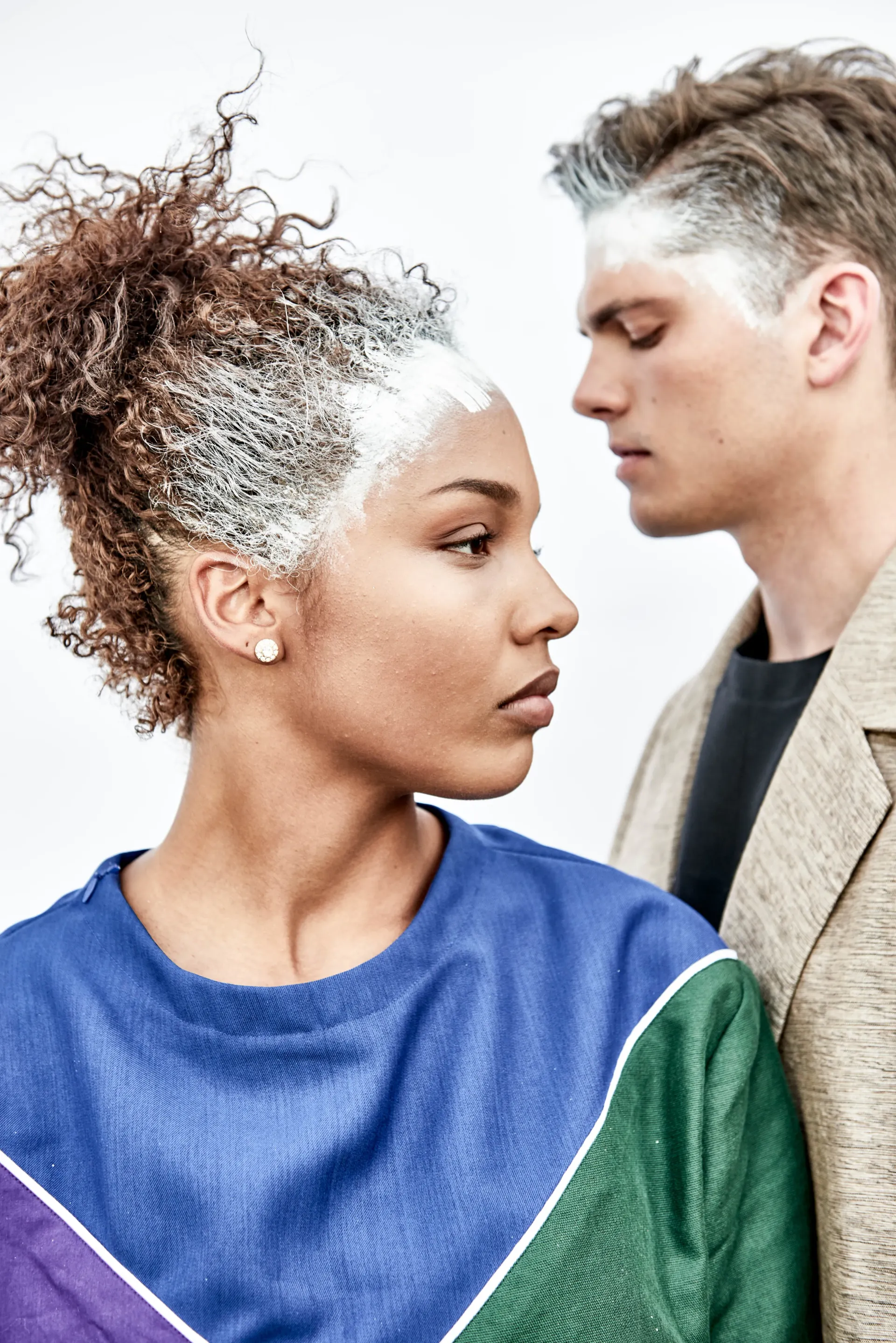 Maennliches und weibliches Model posieren fΓΌr Kleidermarke mit statement Make-Up weiss entlang Haarlinie