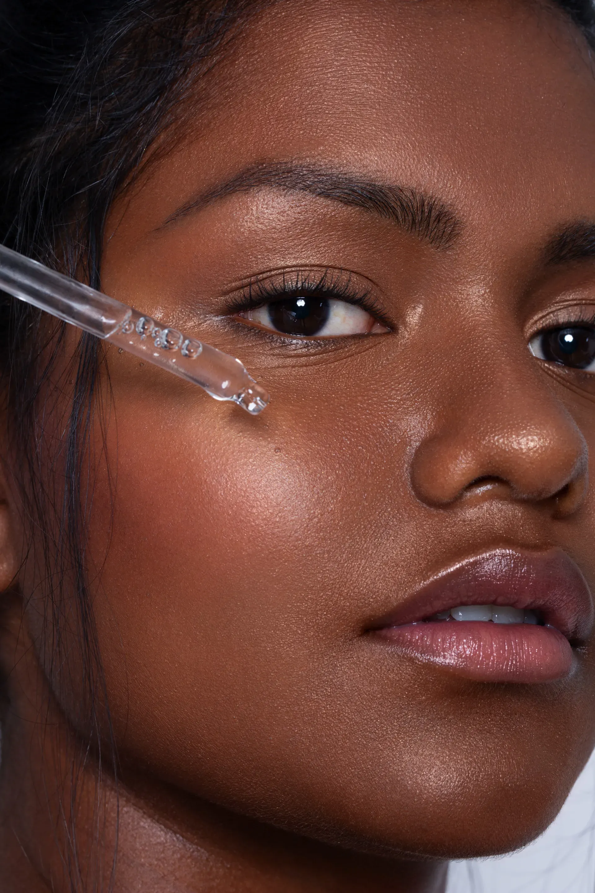 indisches model mit glowy skin fuer werbeaufnahme closeup produkt pipette