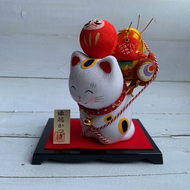 Smiling lucky cat carrying a mascot - Daruma/Taiko drum/fish