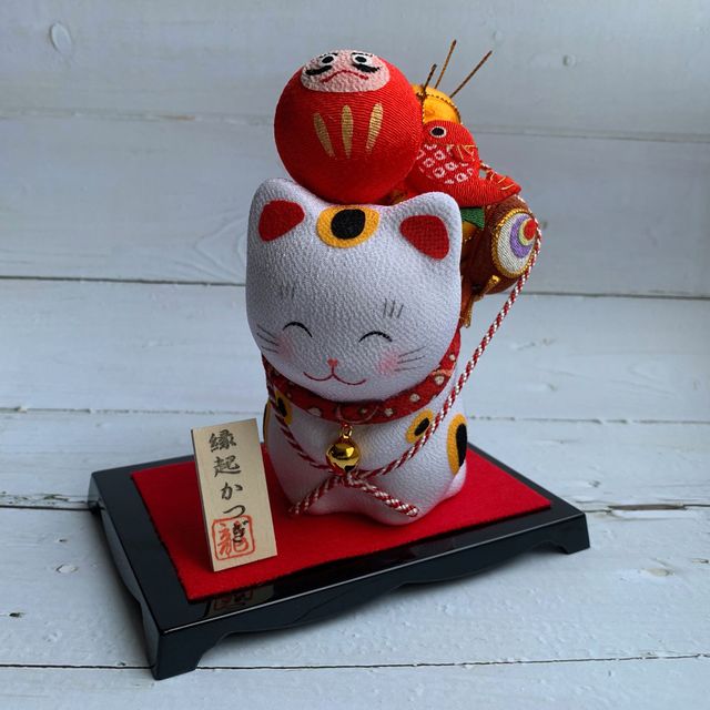 Smiling lucky cat carrying a mascot - Daruma/Taiko drum/fish