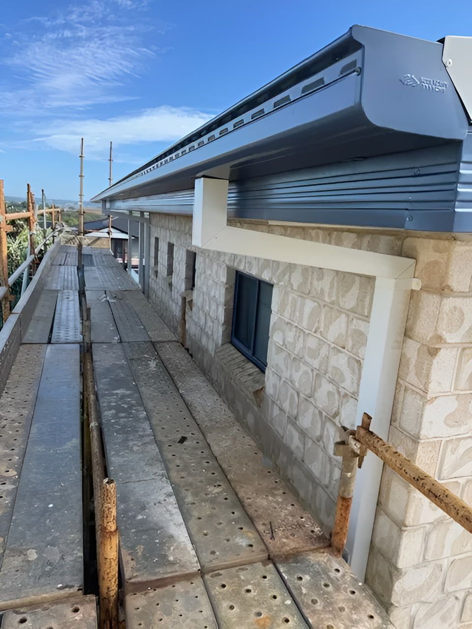 Building exterior under construction with scaffolding and blue sky. — Lee Pakau Roofing & Guttering in Banora Point, NSW