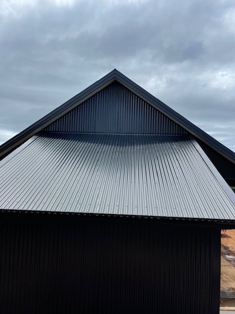 Black Corrugated Metal Roof on a Building With a Triangular Peak — Lee Pakau Roofing & Guttering in Banora Point, NSW