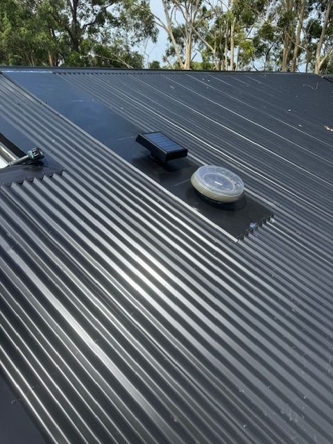 Black Corrugated Metal Roof With Solar Panel and Vent — Lee Pakau Roofing & Guttering in Tweed Heads, NSW