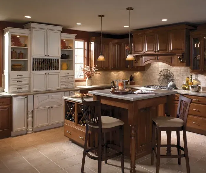 A warm-toned kitchen with white and wood cabinets, an island, and two bar stools.
