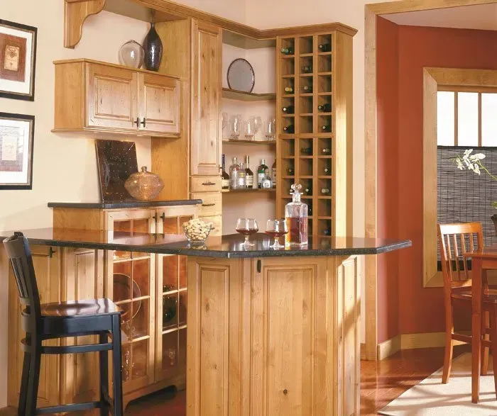 A home bar with wooden cabinets, a granite countertop, and a wine rack.