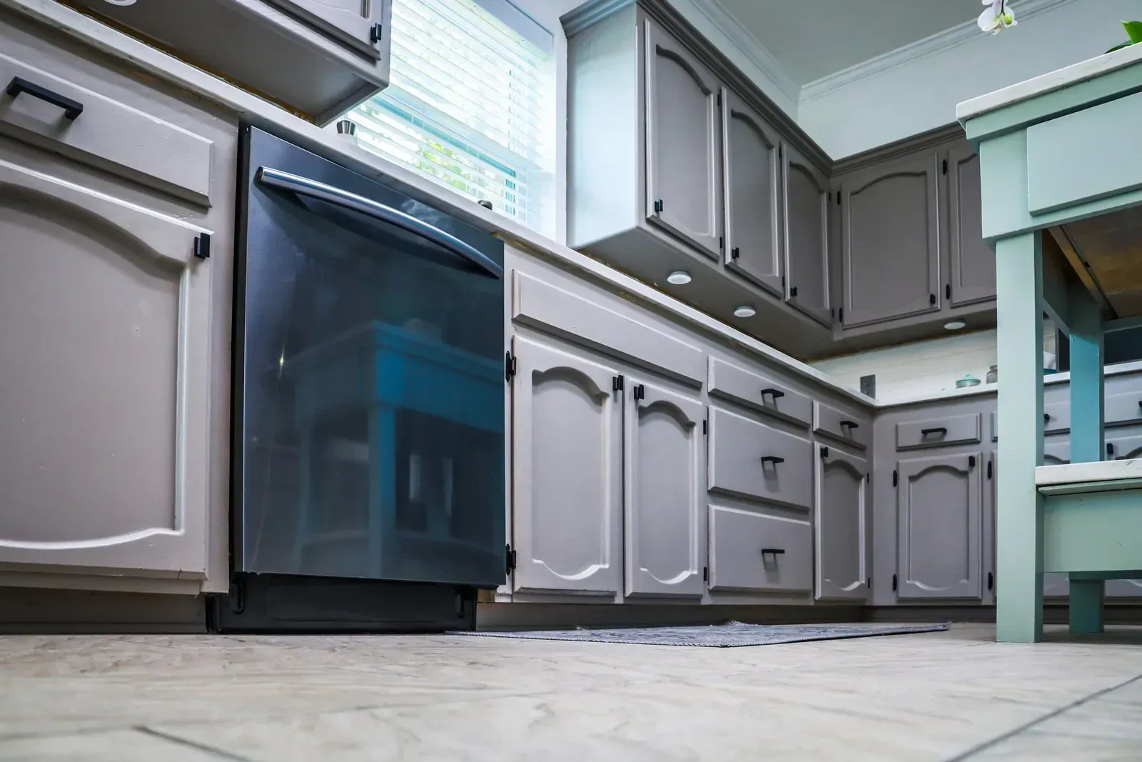 Gray kitchen cabinets and black appliances in a brightly lit room.
