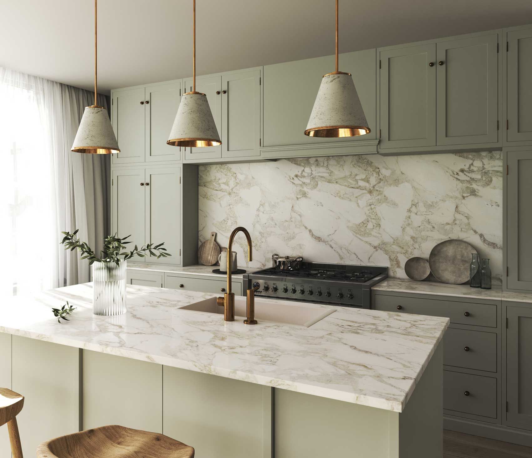 A modern kitchen with sage green cabinets, marble countertops, and gold pendant lights.