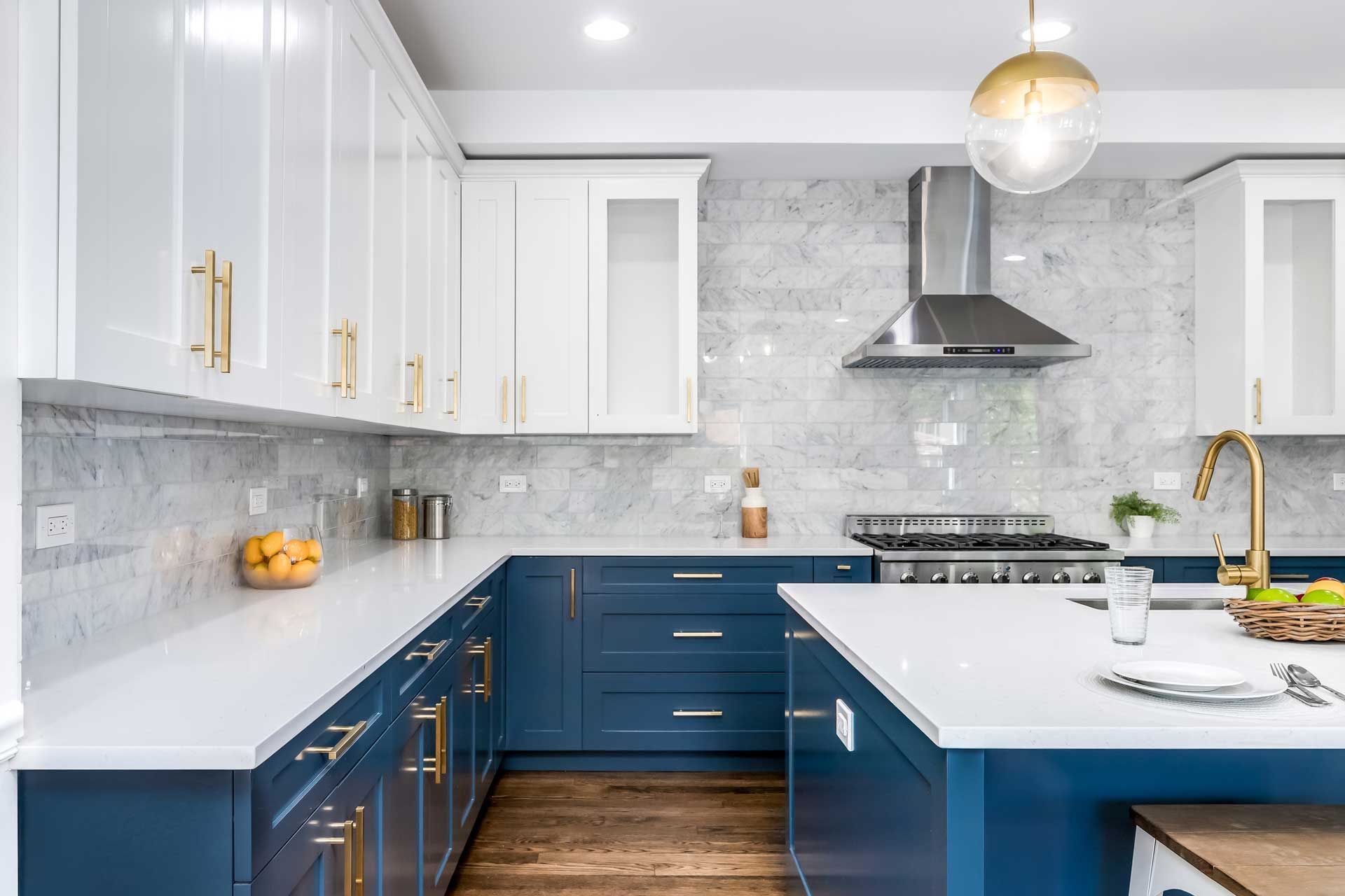 Modern kitchen with white and blue cabinets, stainless steel appliances, and marble backsplash.