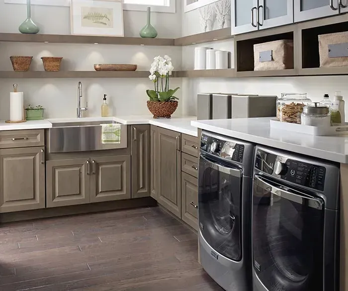 Laundry room with stainless steel sink, washer/dryer, neutral cabinetry, and floating shelves.