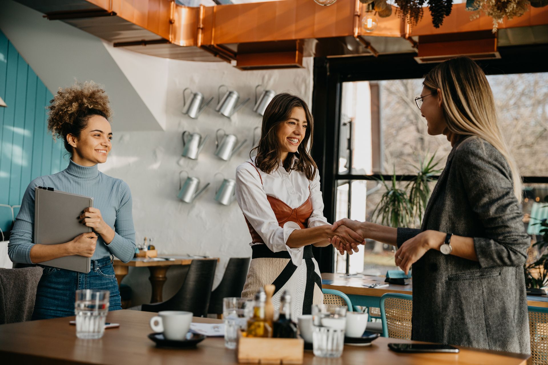 A group of women are shaking hands in a restaurant.