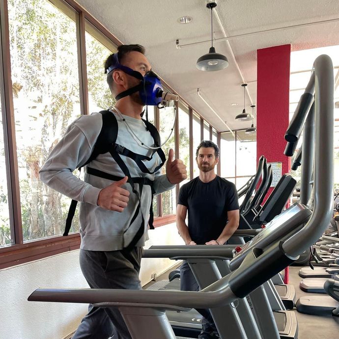 A man wearing a mask is running on a treadmill in a gym