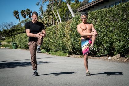 Two men are stretching their legs on the side of the road.