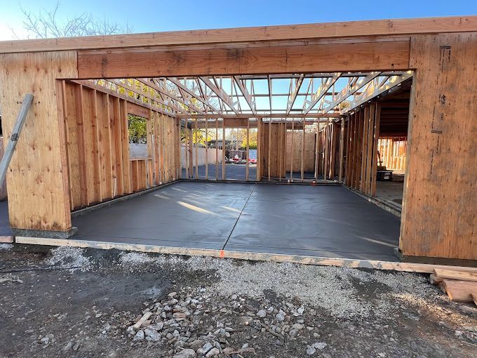 A garage under construction with a concrete floor and wooden walls.