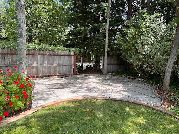 A patio with a wooden fence in the background and flowers in the foreground.