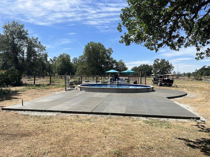 There is a large swimming pool in the middle of a field.